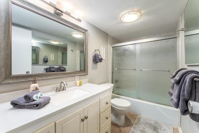 full bathroom with tile patterned floors, combined bath / shower with glass door, a textured ceiling, and vanity