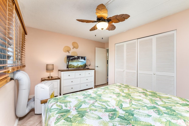 unfurnished bedroom with light tile patterned flooring, ceiling fan, a closet, and a textured ceiling