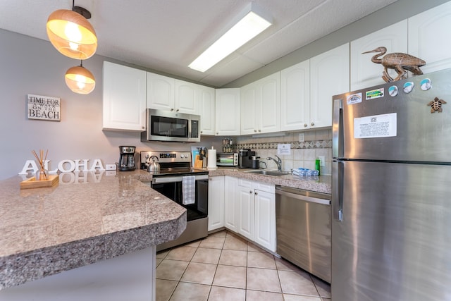 kitchen with white cabinetry, stainless steel appliances, decorative light fixtures, and sink