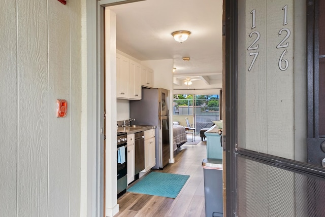 kitchen featuring appliances with stainless steel finishes, ceiling fan, white cabinetry, sink, and light wood-type flooring