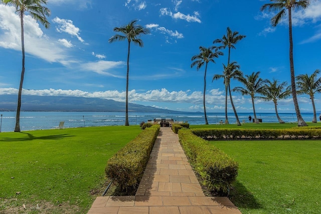 view of property's community with a lawn and a water view