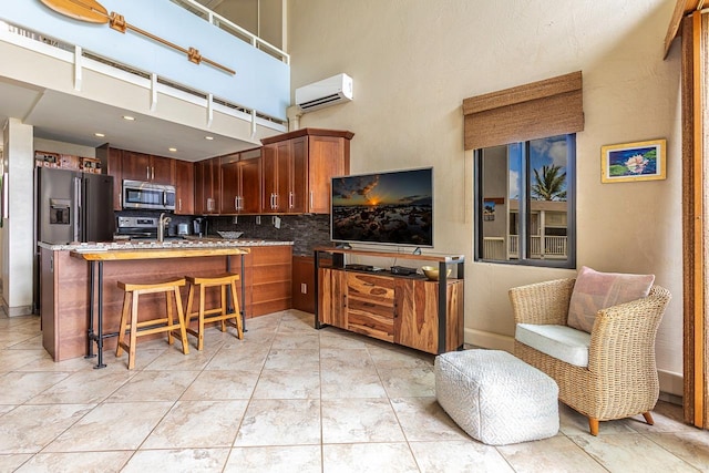 kitchen featuring stone countertops, a kitchen bar, a wall mounted AC, backsplash, and stainless steel appliances