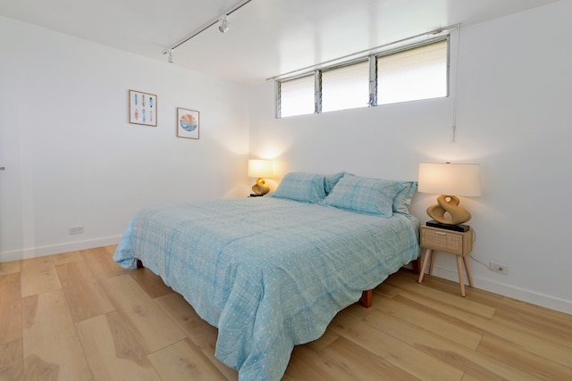 bedroom with light hardwood / wood-style flooring and track lighting