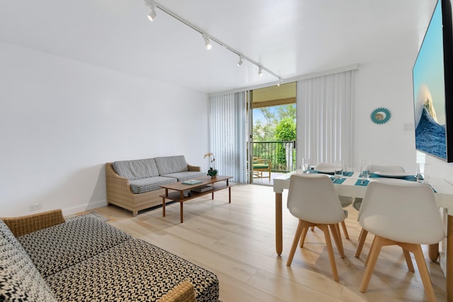 living room with floor to ceiling windows, track lighting, and light wood-type flooring