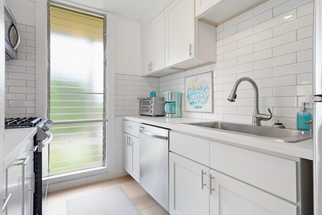 kitchen with white cabinets, appliances with stainless steel finishes, decorative backsplash, and sink