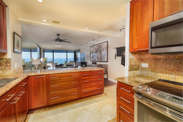 kitchen with track lighting, ceiling fan, appliances with stainless steel finishes, and tasteful backsplash