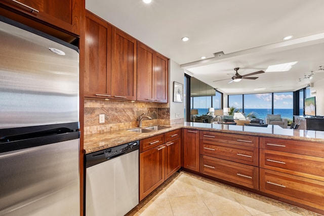 kitchen featuring tasteful backsplash, a sink, appliances with stainless steel finishes, ceiling fan, and light stone countertops