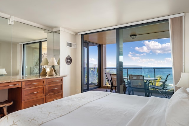 bedroom featuring a water view, visible vents, expansive windows, and access to exterior