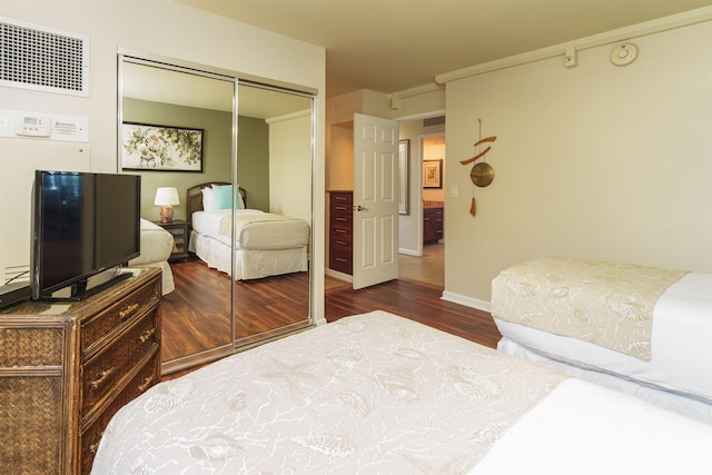 bedroom featuring wood finished floors, visible vents, baseboards, and a closet