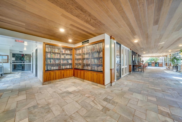 corridor featuring stone tile flooring, built in shelves, and wooden ceiling