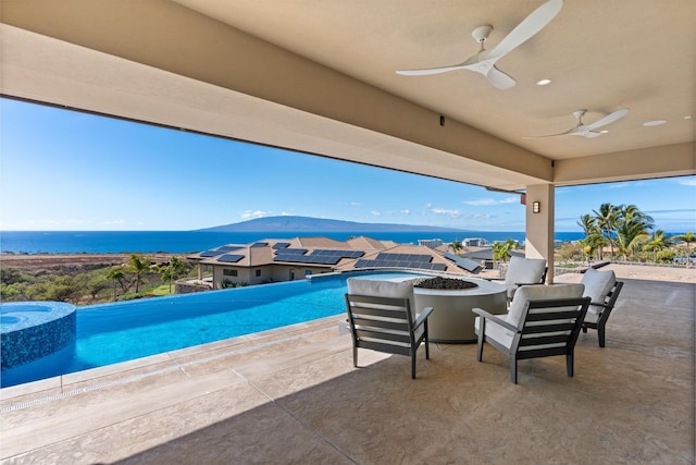 view of swimming pool with ceiling fan, a patio area, a water view, and an outdoor fire pit