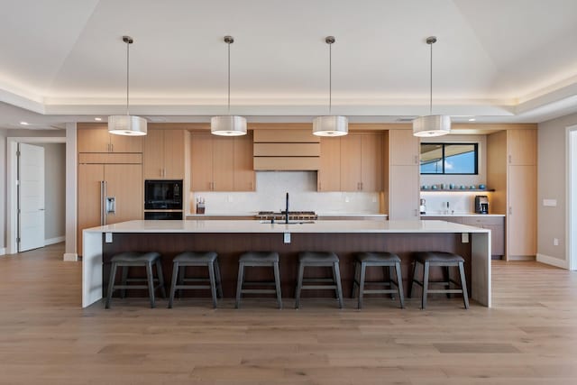 kitchen with a spacious island, decorative light fixtures, and light hardwood / wood-style floors