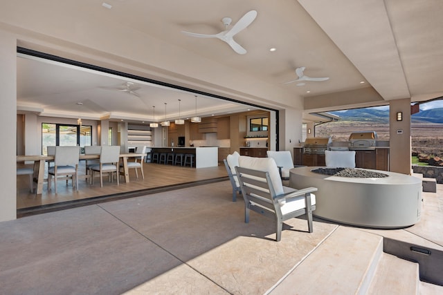 view of patio / terrace featuring ceiling fan, exterior kitchen, an outdoor fire pit, and grilling area