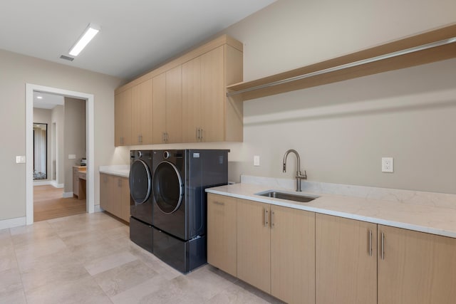 washroom with cabinets, washing machine and dryer, and sink