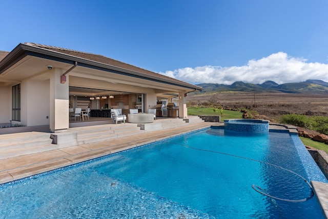 view of swimming pool with an in ground hot tub, a mountain view, and a patio