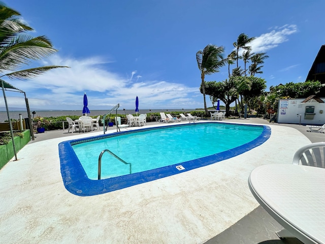 view of swimming pool with a patio and a water view