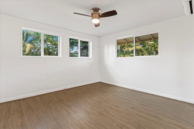 empty room with plenty of natural light, ceiling fan, and dark wood-type flooring