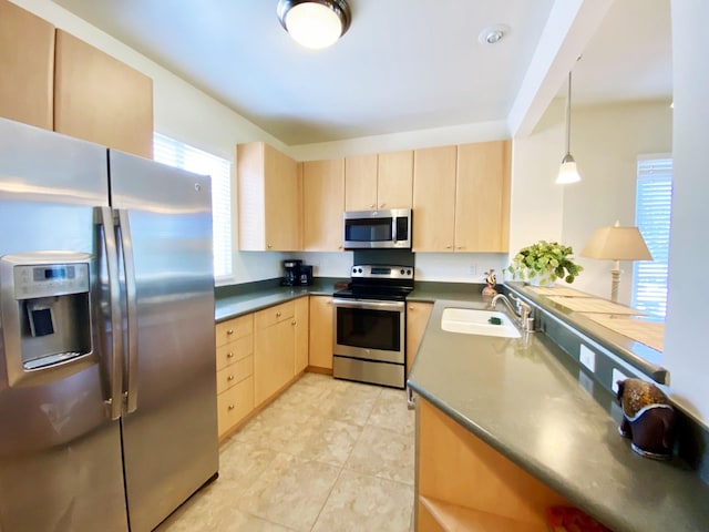 kitchen with light brown cabinetry, stainless steel appliances, sink, and a wealth of natural light