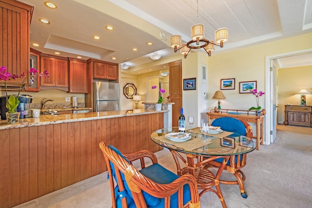 dining space with light colored carpet, an inviting chandelier, a tray ceiling, and sink