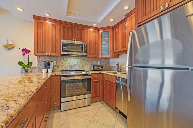 kitchen with light stone counters, light tile patterned flooring, tasteful backsplash, sink, and appliances with stainless steel finishes