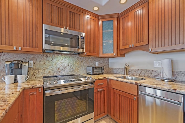 kitchen with stainless steel appliances, light stone counters, tasteful backsplash, and sink