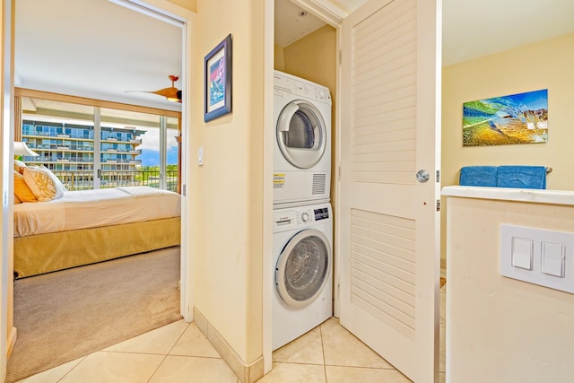 clothes washing area with stacked washer and clothes dryer, light carpet, and ceiling fan