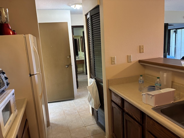 50 Kepuhi Pl Unit 159, Maunaloa, HI 96770 - kitchen with a textured ceiling, freestanding refrigerator, light tile patterned floors, a sink, and light countertops