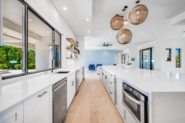 kitchen featuring appliances with stainless steel finishes, ceiling fan, sink, decorative light fixtures, and white cabinetry