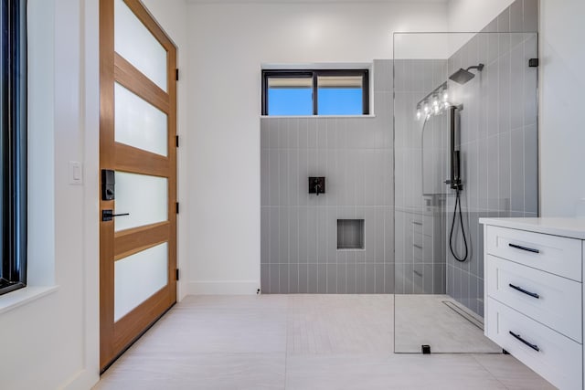 bathroom with tiled shower, vanity, and tile patterned floors