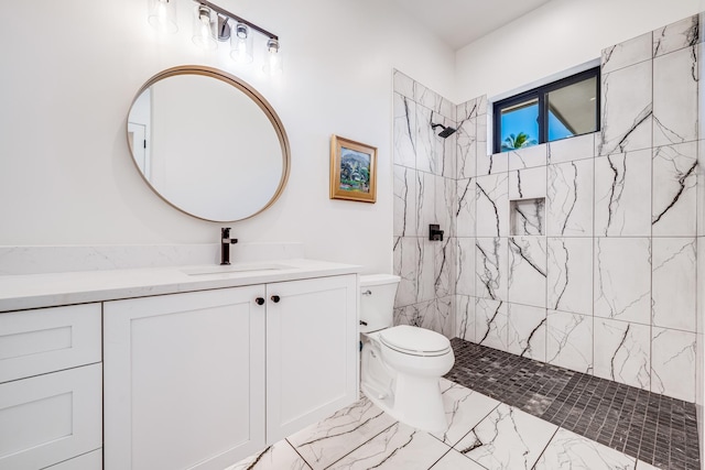 bathroom featuring a tile shower, vanity, and toilet