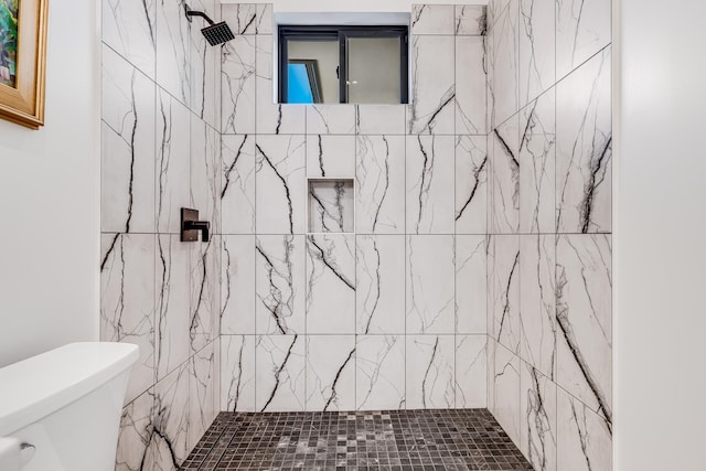 bathroom featuring tiled shower and toilet