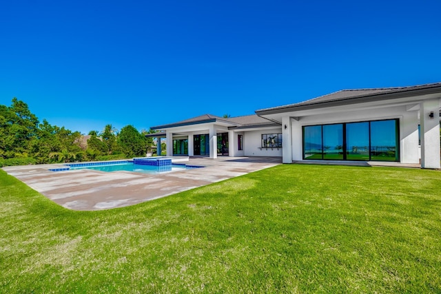 back of property featuring a swimming pool with hot tub, a patio, and a lawn