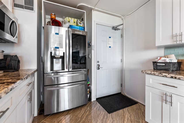 kitchen featuring appliances with stainless steel finishes, white cabinetry, tasteful backsplash, and light stone counters