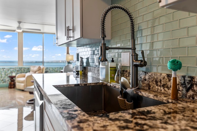 kitchen with stone countertops, a sink, and decorative backsplash