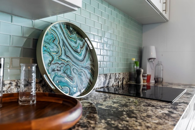 detailed view of decorative backsplash and black electric cooktop