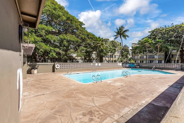 community pool with fence and a patio area