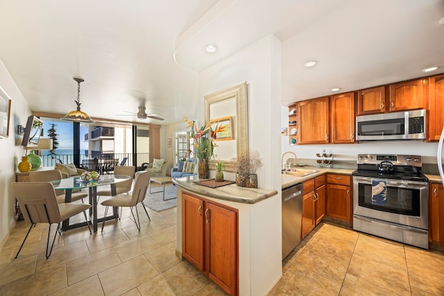 kitchen with kitchen peninsula, stainless steel appliances, ceiling fan, sink, and pendant lighting