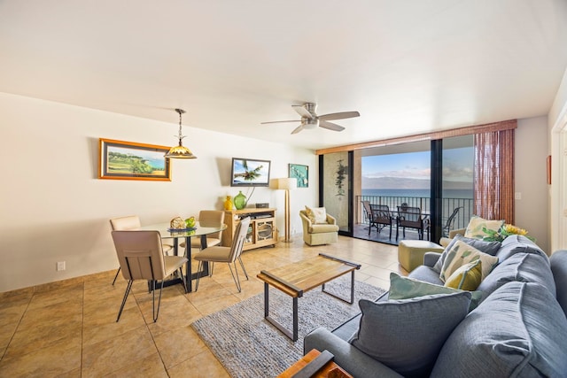 living room featuring expansive windows, ceiling fan, a water view, and light tile patterned floors