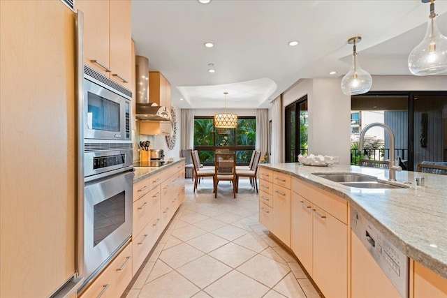 kitchen with appliances with stainless steel finishes, pendant lighting, light brown cabinetry, and sink