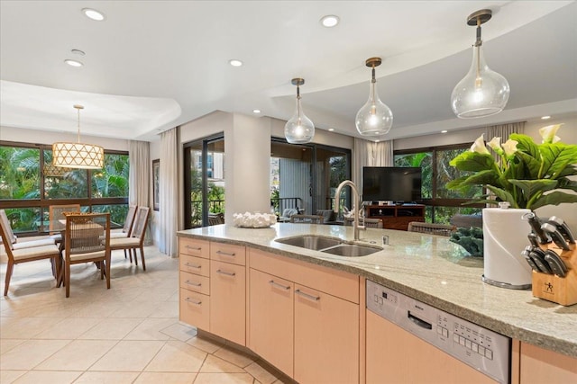 kitchen featuring light brown cabinetry, sink, light stone countertops, hanging light fixtures, and stainless steel dishwasher