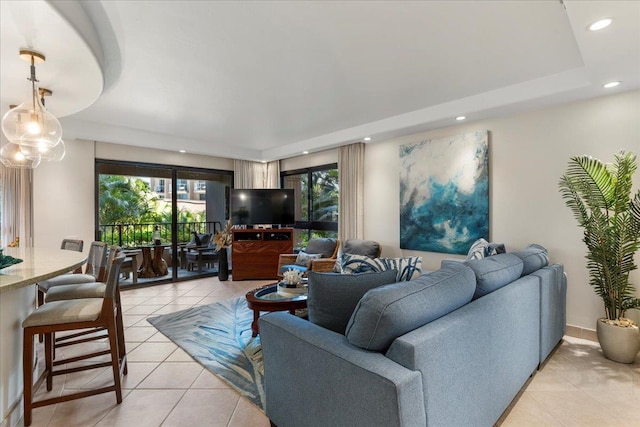 living room featuring a raised ceiling and light tile patterned floors