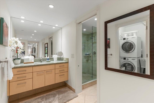 bathroom featuring vanity, stacked washer / dryer, tile patterned flooring, and a shower with door