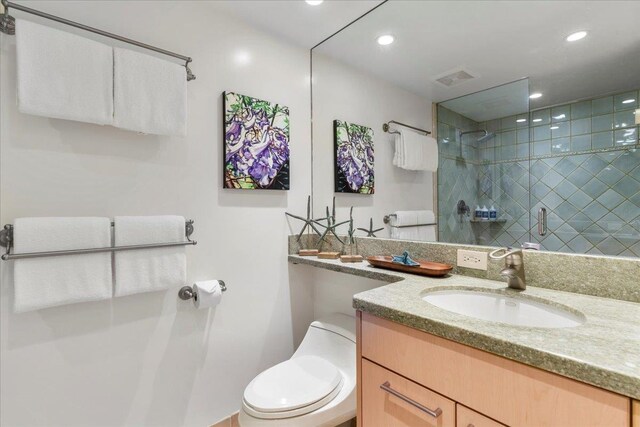 bathroom with a tile shower, vanity, and toilet