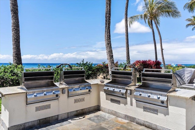 view of patio / terrace featuring grilling area, a water view, and exterior kitchen