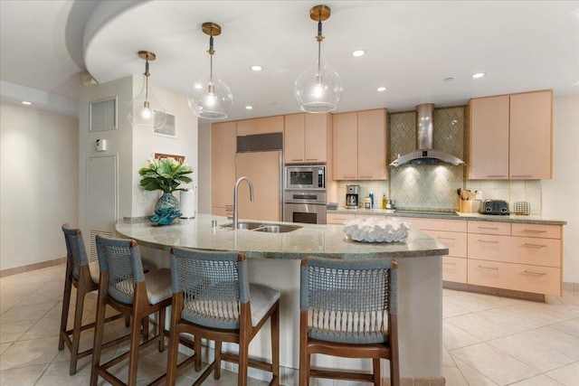 kitchen featuring wall chimney range hood, light brown cabinets, sink, kitchen peninsula, and built in appliances