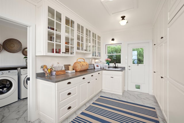 kitchen with separate washer and dryer, white cabinetry, ornamental molding, and sink