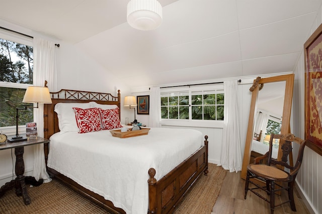 bedroom featuring multiple windows, vaulted ceiling, and hardwood / wood-style flooring