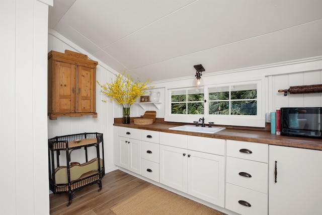 kitchen featuring hardwood / wood-style floors, lofted ceiling, butcher block counters, and sink