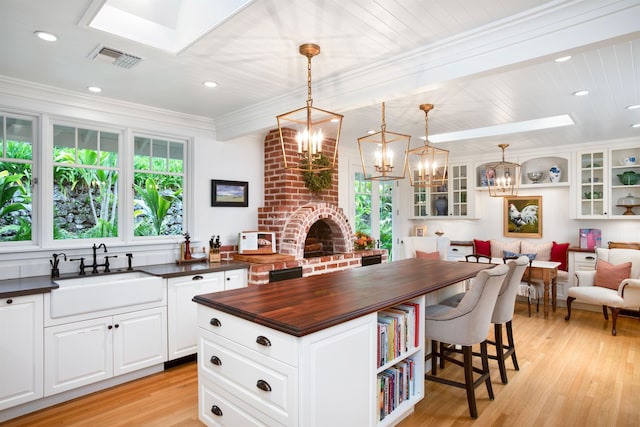 kitchen featuring sink, white cabinets, pendant lighting, and light hardwood / wood-style flooring