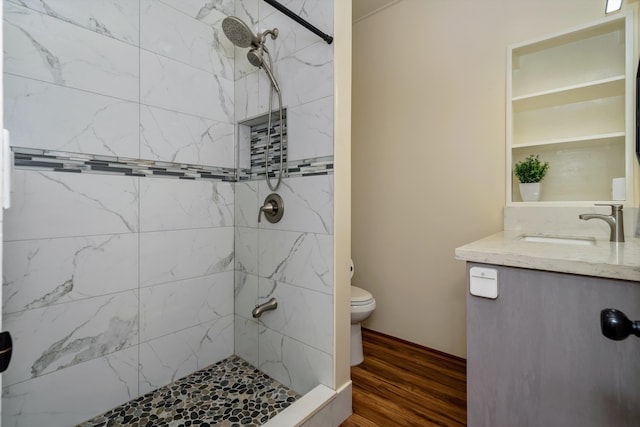 bathroom featuring vanity, hardwood / wood-style floors, toilet, and tiled shower